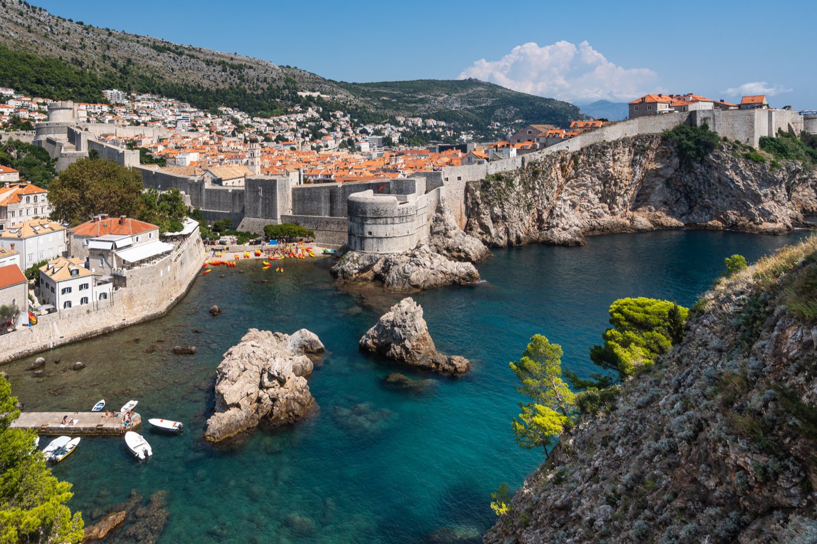 Stadtmauer und Festung von Dubrovnik über einer türkisfarbenen Bucht