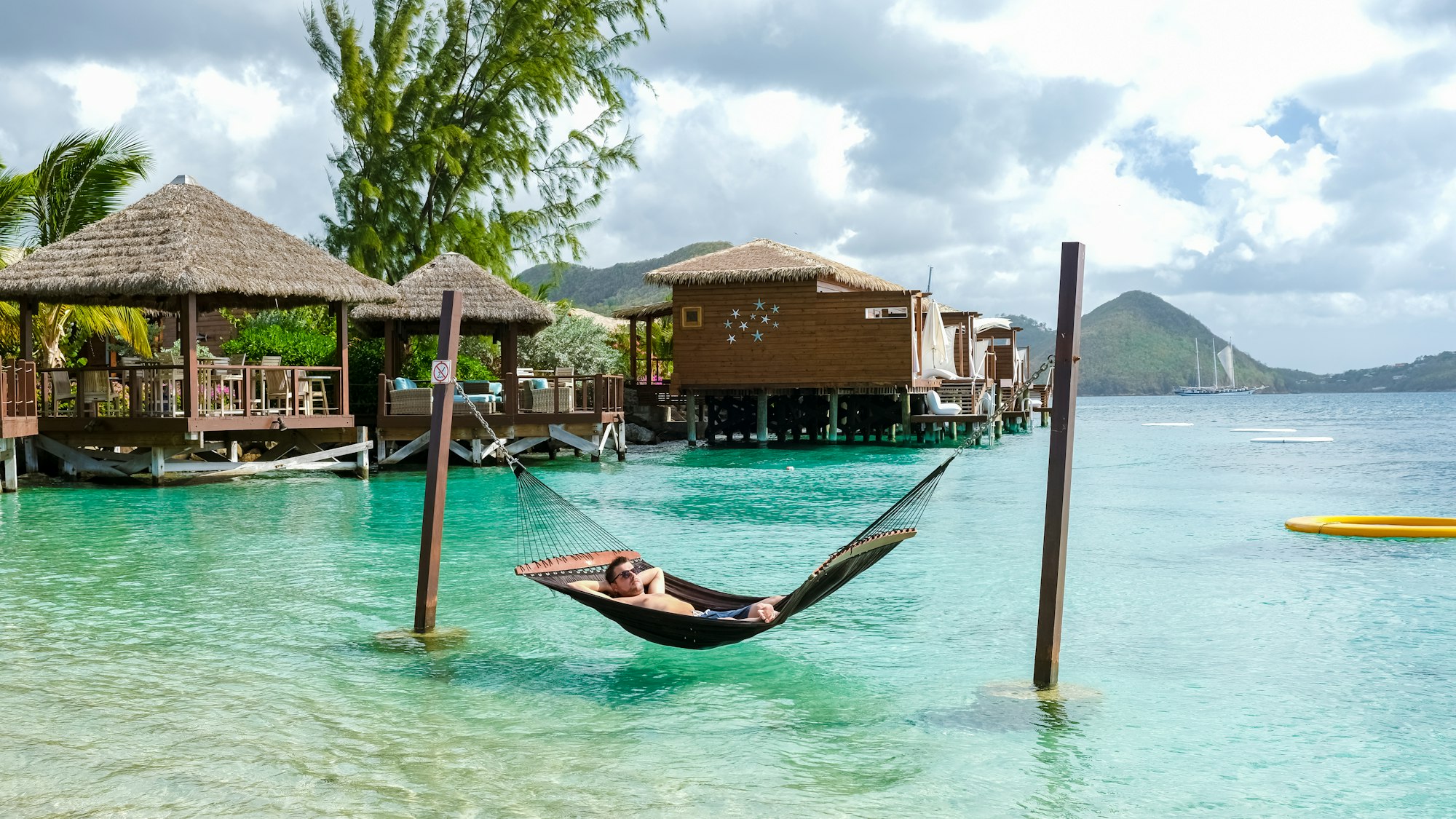 young men in hammock in the ocean at the beach of the tropical Island in the Caribbean