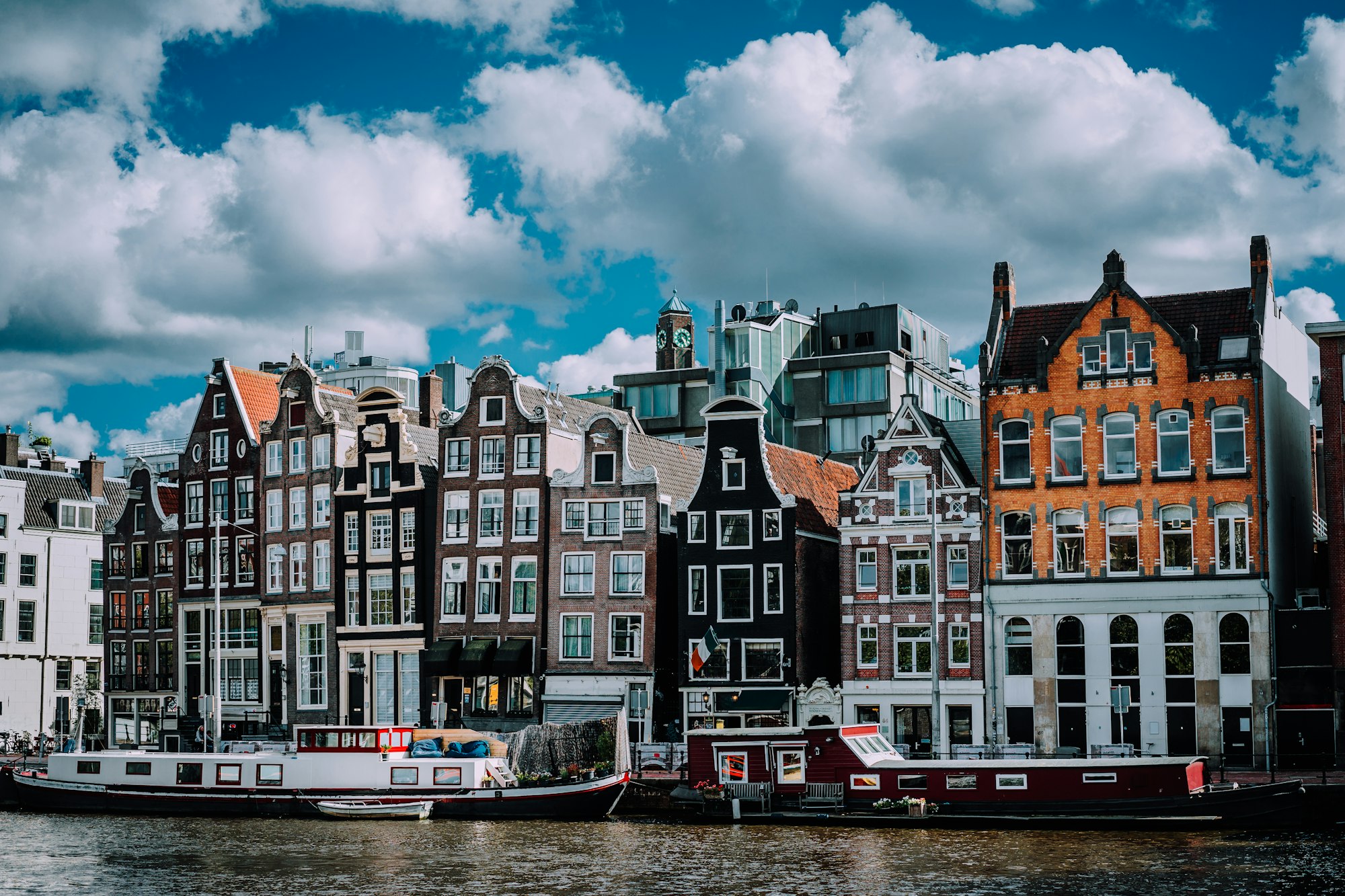 Wonderful architecture of Amsterdam. White fluffy clouds over Leaning Houses Amsterdam, Netherlands